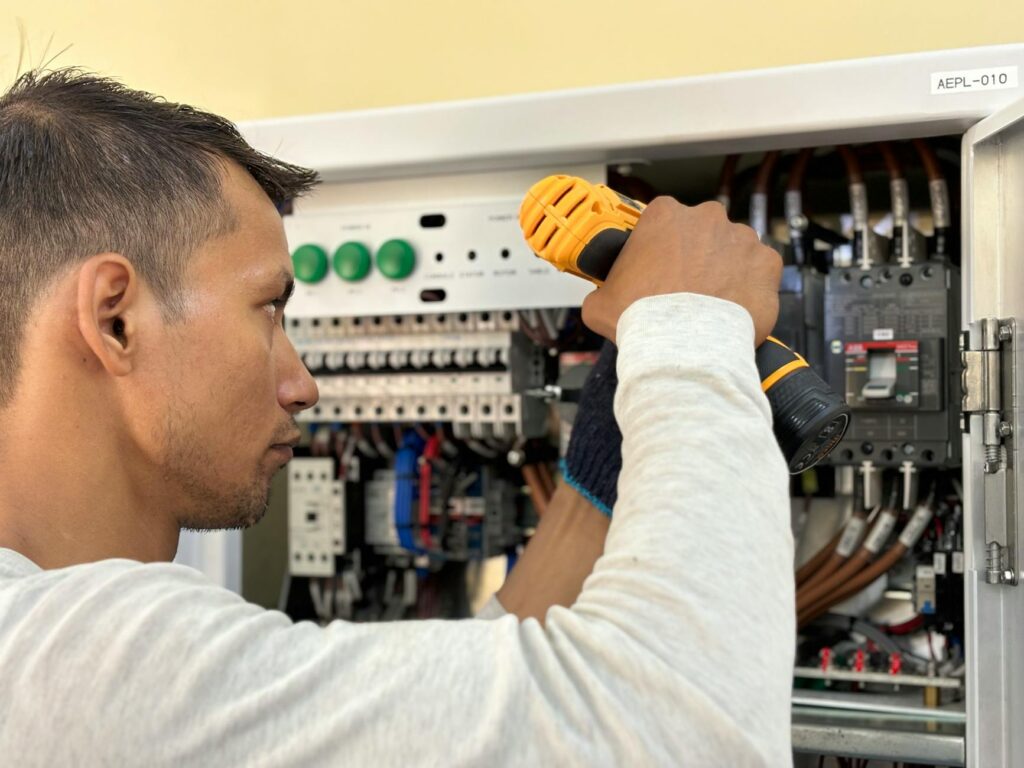 electrician inspecting residential circuit breaker panel and dim light bulb